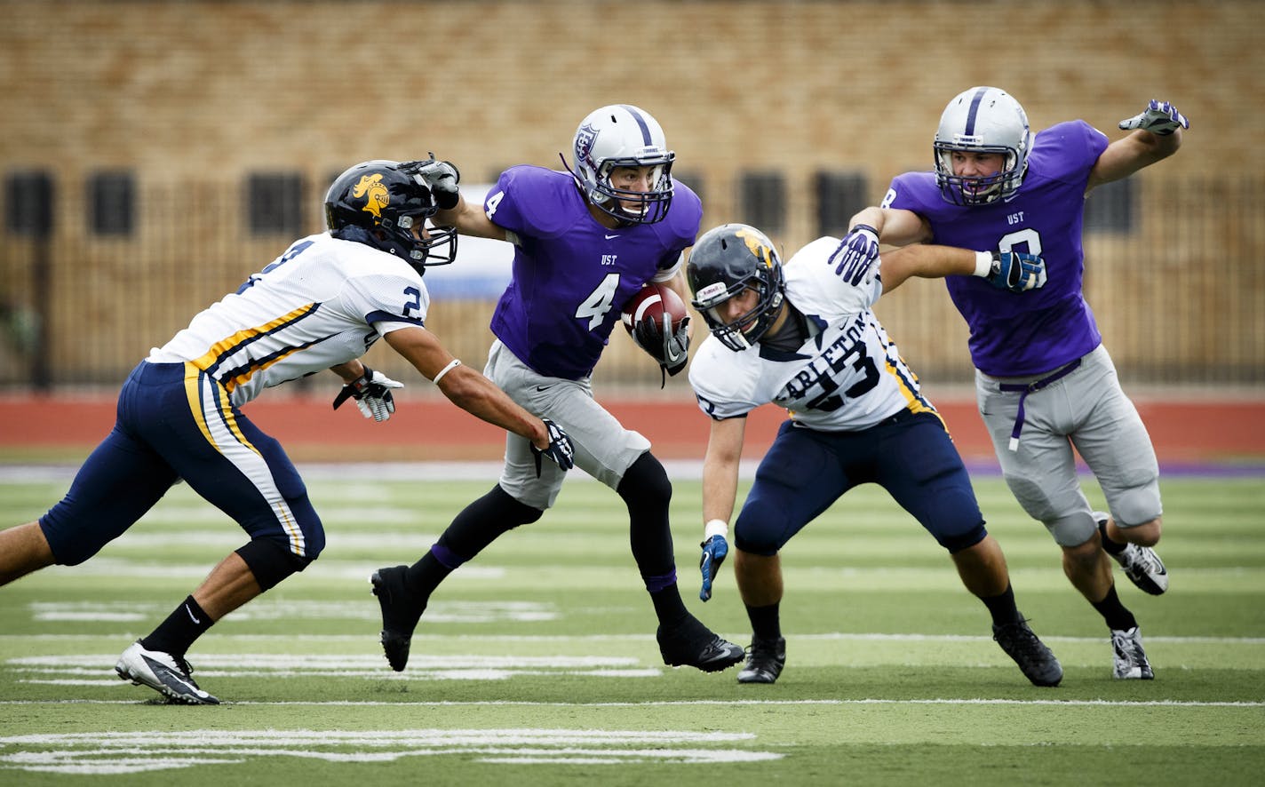 Jack Gilliland (4) stiff arms a defender as Charlie Dowdie (8) blocks during the homecoming football game between UST and Carleton College on Palmer Field at O'Shaughnessy Stadium on October 5, 2013. The Tommies defeated Carleton by a final score of 65-6.