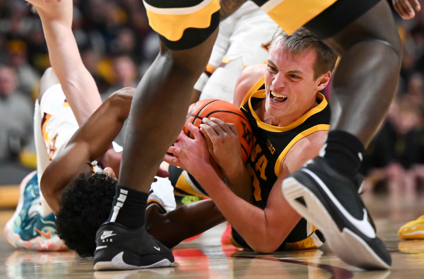 Iowa Hawkeyes forward Payton Sandfort (20) and Minnesota Gophers guard Cam Christie (24) battle for a loose ball in the second half Monday, Jan. 15, 2024 at Williams Arena in Minneapolis, Minn..