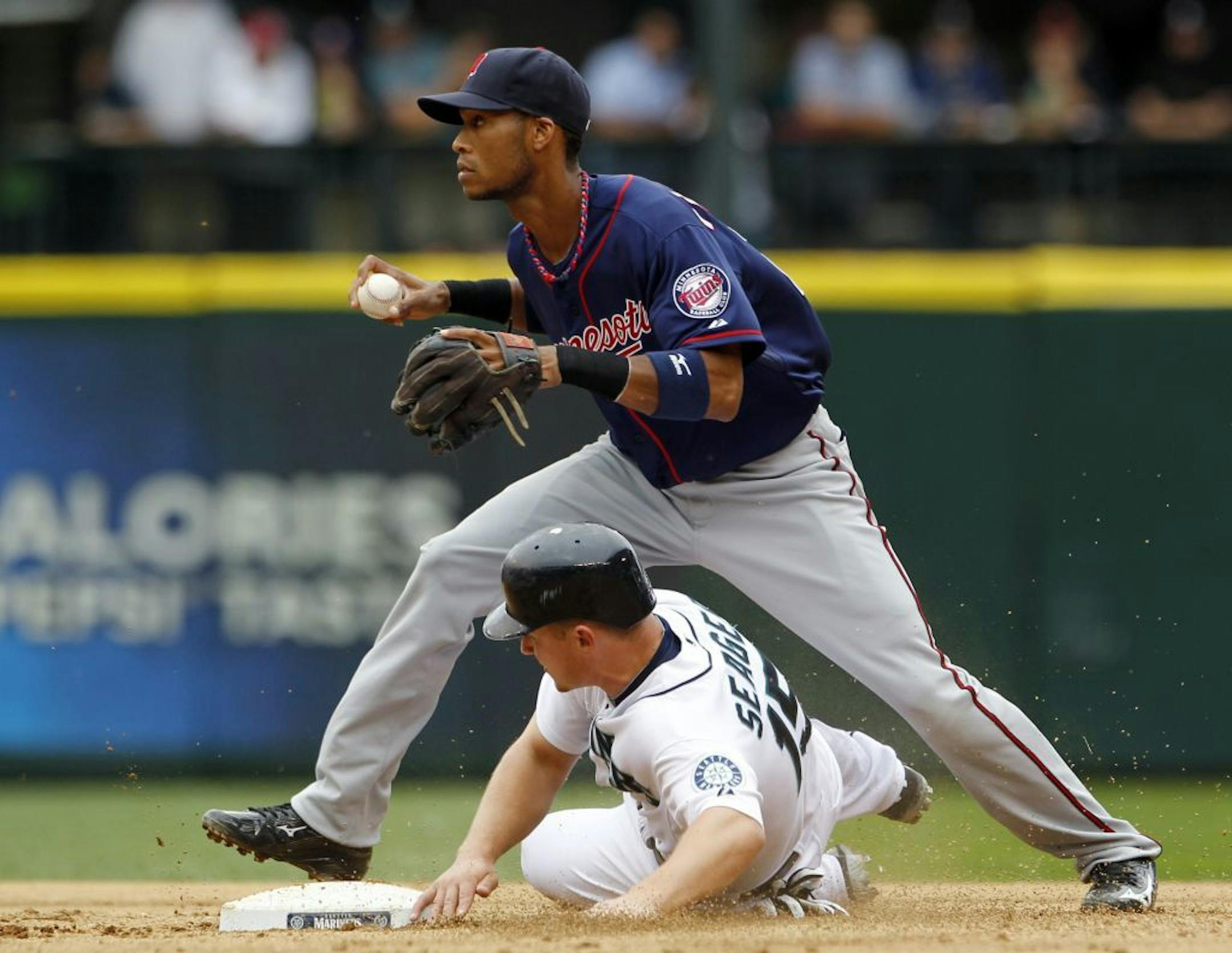 Minnesota Twins shortstop Pedro Florimon, top, turns toward the infield after forcing out Seattle Mariners' Kyle Seager, bottom, in the fifth inning of a baseball game Sunday, Aug. 19, 2012, in Seattle. Seager's slide broke up a possible double play, leaving John Jaso safe at second with a fielder's choice.