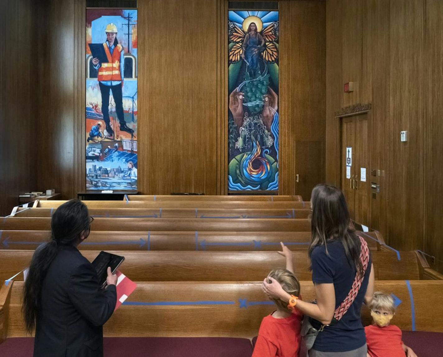 St. Paul and Ramsey County leaders unveiled the new murals in its historic meeting chambers. The new pieces done by diverse group of artists will cover the old 1930s murals of white men towering over Native Americans and laborers. Here, Artist Gustavo Lira (left), one of the artists from CLUES Latinx Mural Apprenticeship Project, that produced the mural at right, admired the murals with Leah Young and her two sons Dag, 9, and Soren, 5. The mural at left was done by Adam Swanson of Cloquet. brian