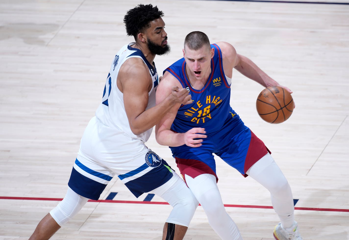 Denver Nuggets center Nikola Jokic, right, drives to the rim as Minnesota Timberwolves center Karl-Anthony Towns defends in the first half of Game 1 of an NBA basketball first-round playoff series, Sunday, April 16 2023, in Denver. (AP Photo/David Zalubowski)