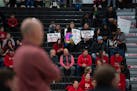 Eden Prairie Eagles head coach David Flom coached from the sideline, foreground, while half a dozen people in the stands held up signs during the Eden