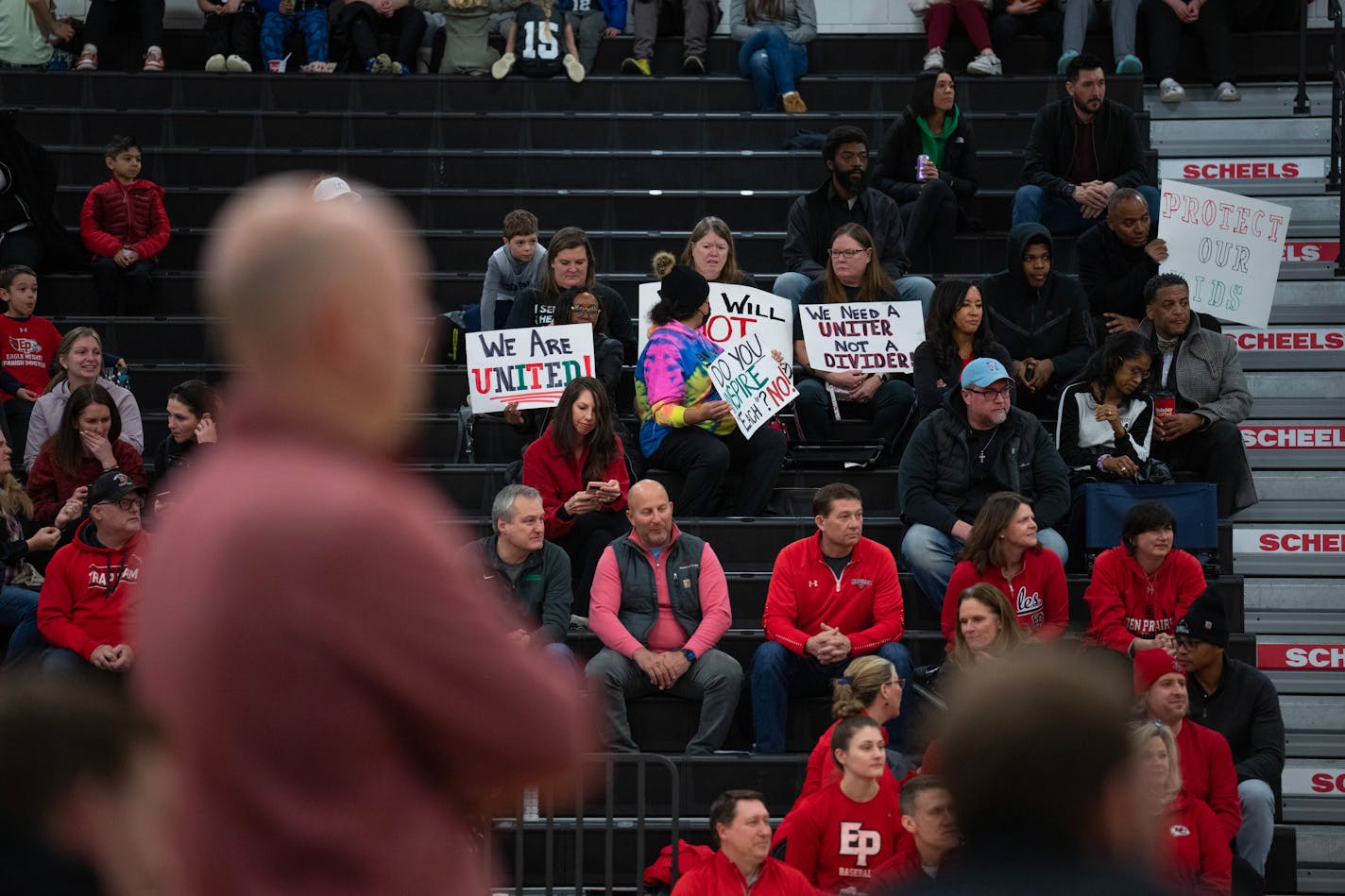 Eden Prairie Eagles head coach David Flom coached from the sideline, foreground, while half a dozen people in the stands held up signs during the Eden Prairie boys Section 2AAAA basketball tournament game against Prior Lake Wednesday night, March 8, 2023 at Eden Prairie High School. Controversy over the reinstatement of head basketball coach David Flom hasn't died down after he served a three game suspension in January. ] JEFF WHEELER • jeff.wheeler@startribune.com