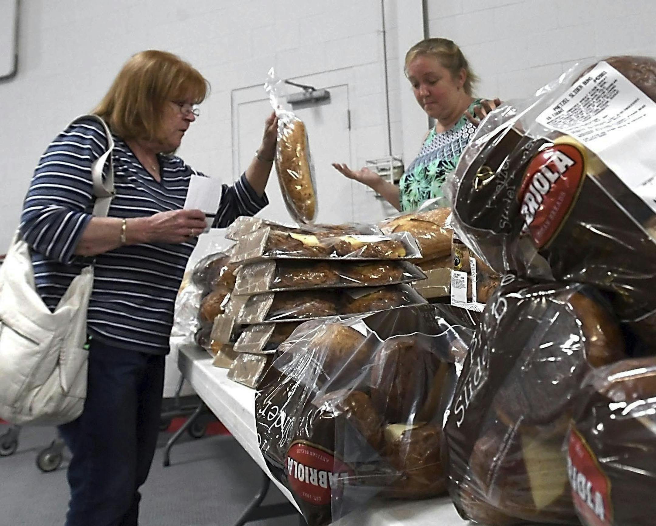 ADVANCE FOR MONDAY JUNE 26 AND THEREAFTER - A Fare for All visitor looks through the bread options at New Creation World Outreach Church in Mankato, Minn. The reduced price grocery service swings through the church each month, giving cost-conscious consumers another option for stocking up on fresh veggies and select meats. (Pat Christman/The Free Press via AP) ORG XMIT: MNMAN101