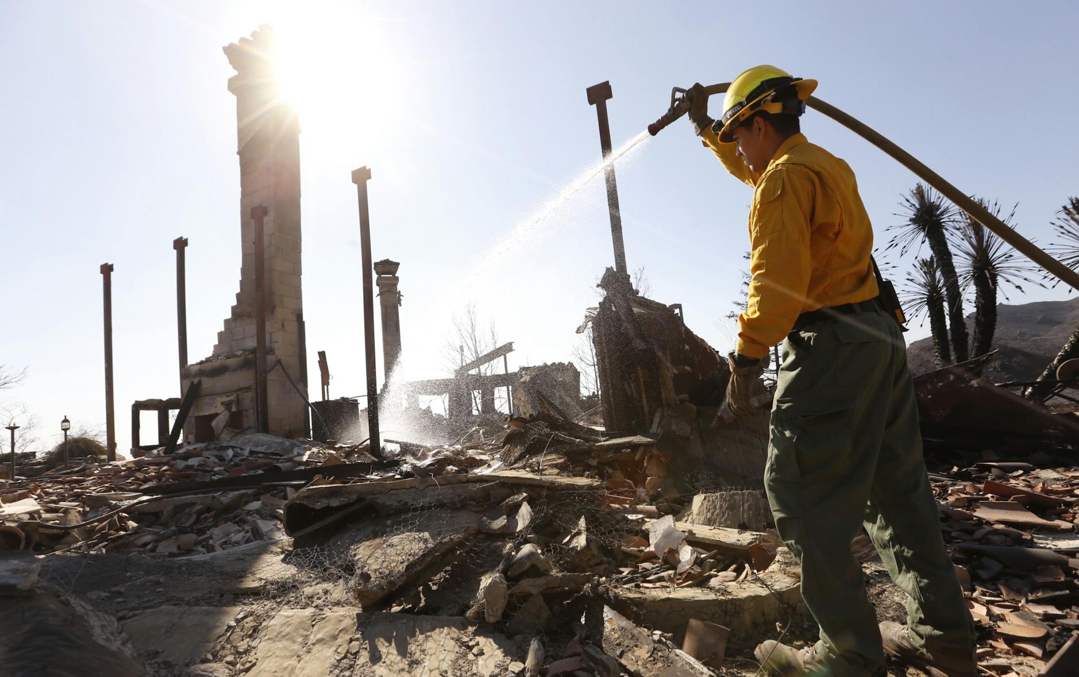 Firefighter Adam Rodriguez from Eloy, Ariz., puts foam on a hotspot of a home on Mulholland Drive on Nov. 12, 2018 in the Malibu Hills destroyed by the Woolsey fire. Two vehicles removed from the long driveway of the home are suspected to be the location where two people lost their lives in the fire storm(Al Seib/Los Angeles Times/TNS) ORG XMIT: 1245391