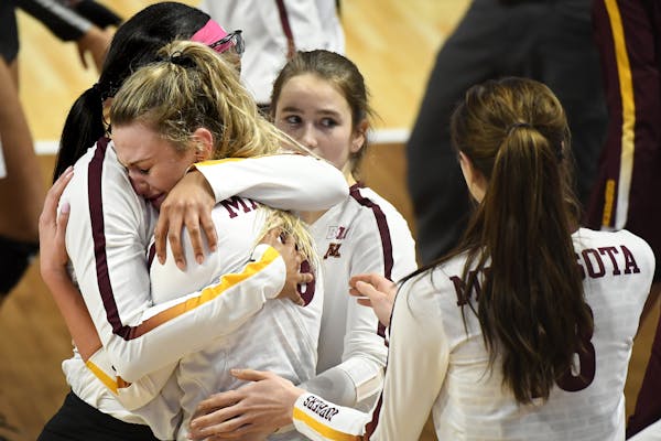 Minnesota setter Samantha Seliger-Swenson (13) was comforted by teammates as she hugged middle blocker Taylor Morgan (12) following their team's 3-1 l