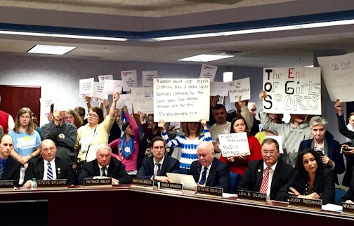 Protestors on both sides of the argument stand behind Minnesota State High School League board members during Thursday's discussion on eligibility policies for transgender athletes. ] Leila Navidi/Star Tribune