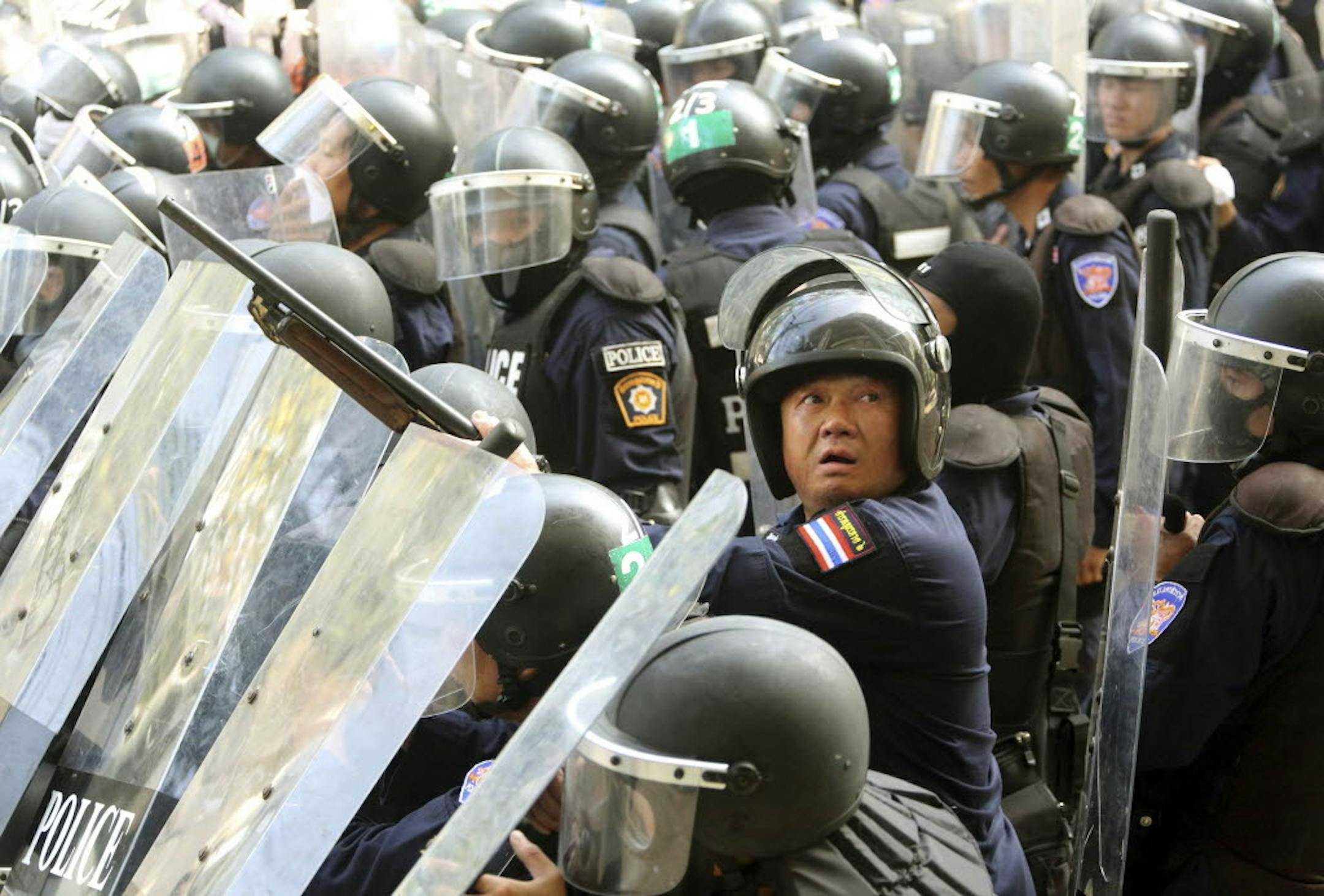 Dec. 26, 2013: A Thai riot policeman, center, holds his rifle loaded with rubber bullets while taking position with fellow officers during a clash with anti-government protesters at the Labor Ministry in Bangkok, Thailand.