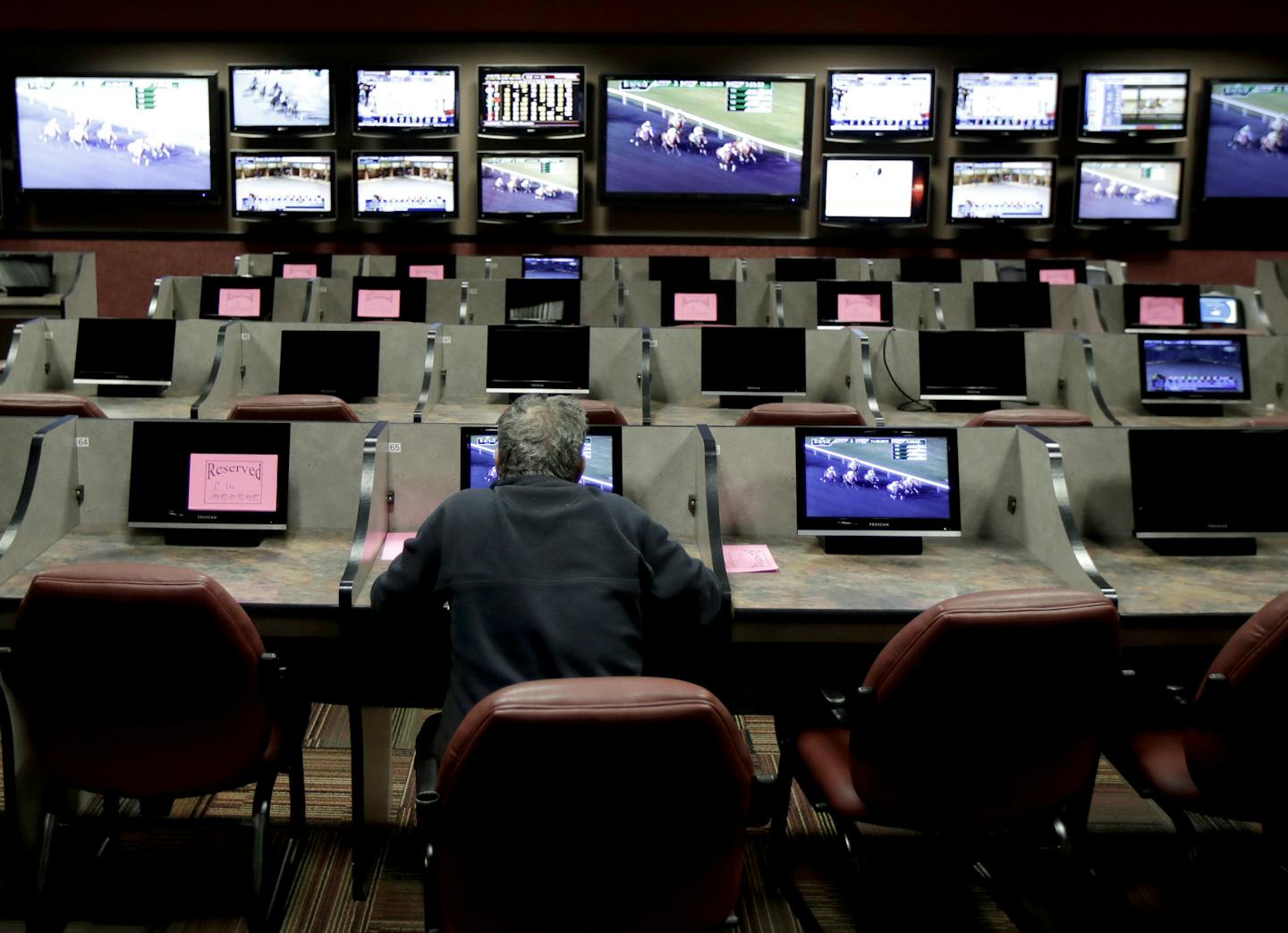 In this Nov. 30, 2017, photo, a man sits at a cubicle watching a simulcast horse race at the Monmouth Park racetrack in West Long Branch, N.J. With banks of TVs tuned to all-sports stations and a spacious bar, the lounge a the racetrack is a sports gamblers&#xed; paradise-in-waiting. All that&#xed;s standing in its way: A 25-year-old federal law that bars betting on sports in most states. The high court is weighing On Dec. 4, whether a federal law that prevents states from authorizing sports bet