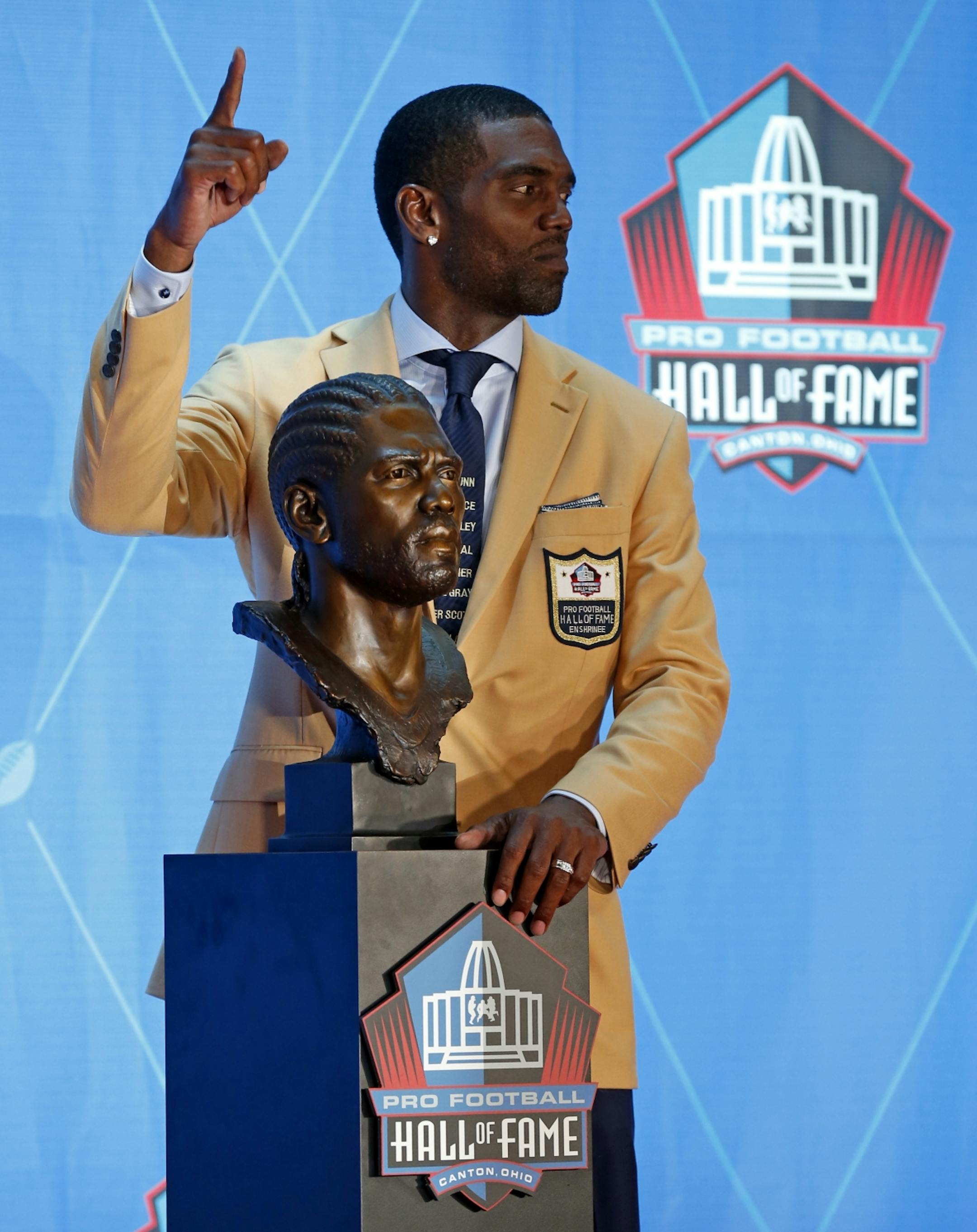 Former NFL player Randy Moss poses with a bust of himself during an induction ceremony at the Pro Football Hall of Fame, Saturday, Aug. 4, 2018 in Canton, Ohio.