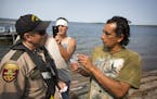 DNR conservation officer Tim Collette gives a citation to Jim Northrup (right) and Todd Thompson, (with phone) for Taking Fish by Illegal Methods for 