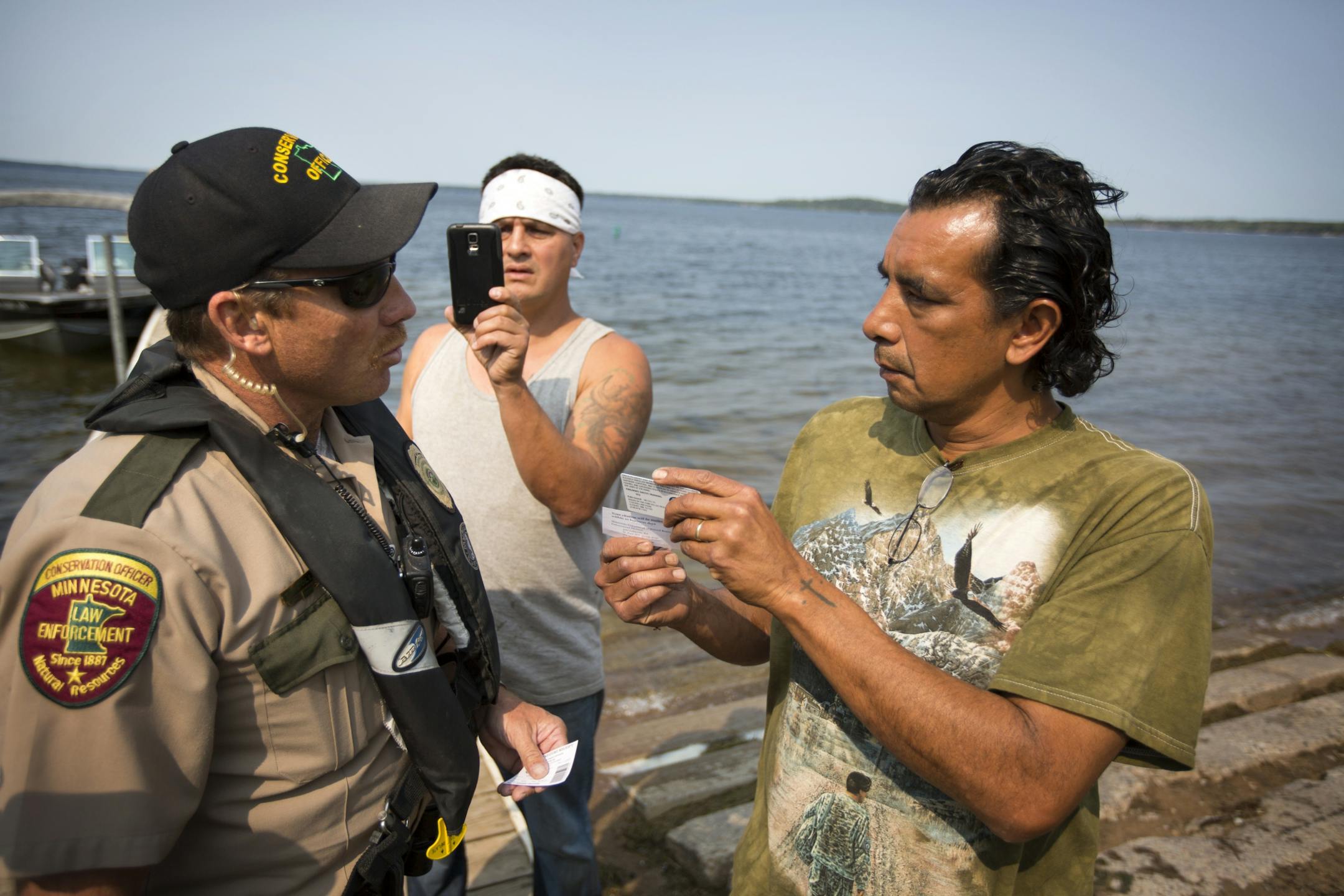 DNR conservation officer Tim Collette gives a citation to Jim Northrup (right) and Todd Thompson, (with phone) for Taking Fish by Illegal Methods for setting a gill net on Gull Lake Friday morning.