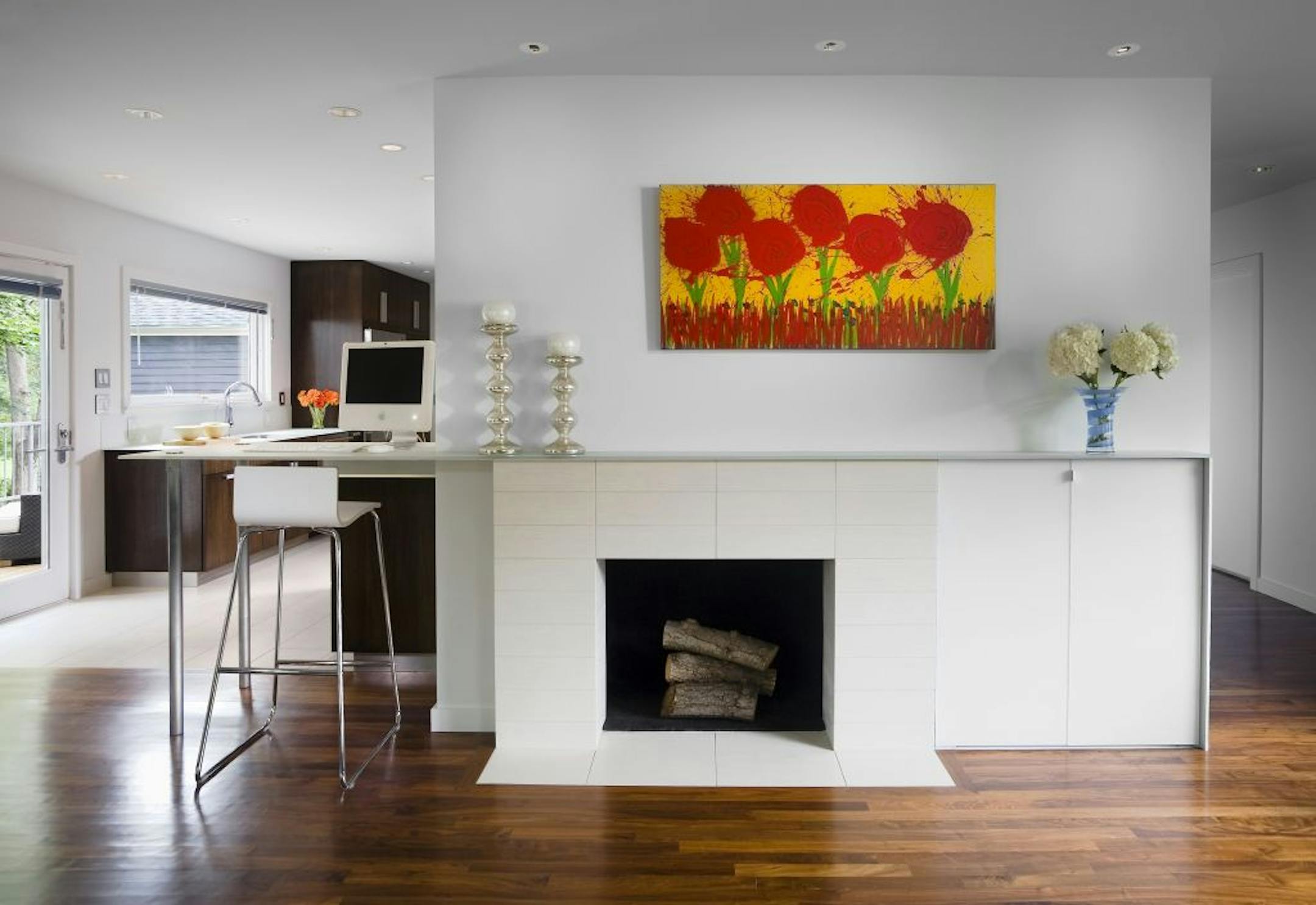 Modern remodeled living room showing fireplace and part of kitchen with computer desk