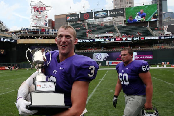 St. Thomas wide receiver Tanner Vik carried the Holy Grail trophy after the Tommies beat St. John's at Target Field on Sept. 23, 2017.