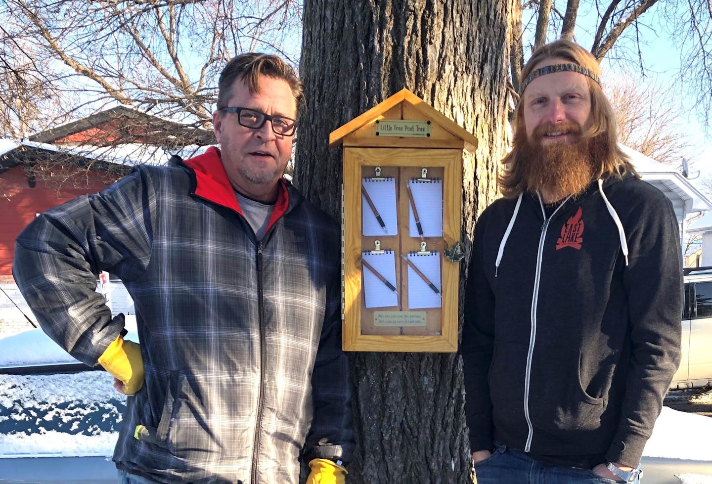 photo of two men standing by a tree on a snowy day