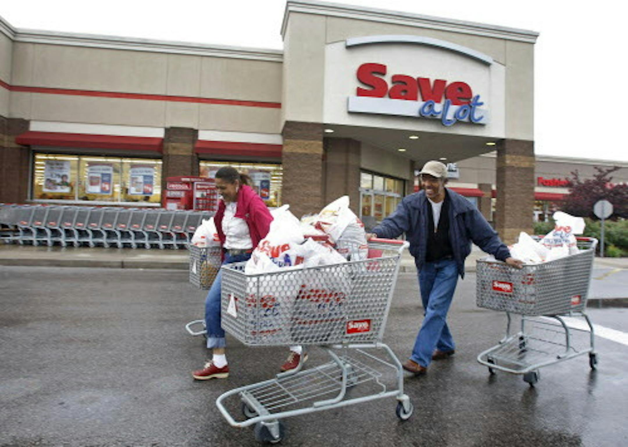 Shoppers Camelious Thompson and her brother Mark Eaton leave a Save-A-Lot store in St. Louis, Missouri, U.S., on Thursday, May 20, 2010. Supervalu Inc.'s Save-A-Lot unit, a discount grocer specializing in store-brand products, plans to expand in urban areas to fill in gaps left after larger chains moved to the suburbs. Photographer: Peter Newcomb/Bloomberg *** Local Caption *** Camelious Thompson; Mark Eaton ORG XMIT: MIN2012120516120005