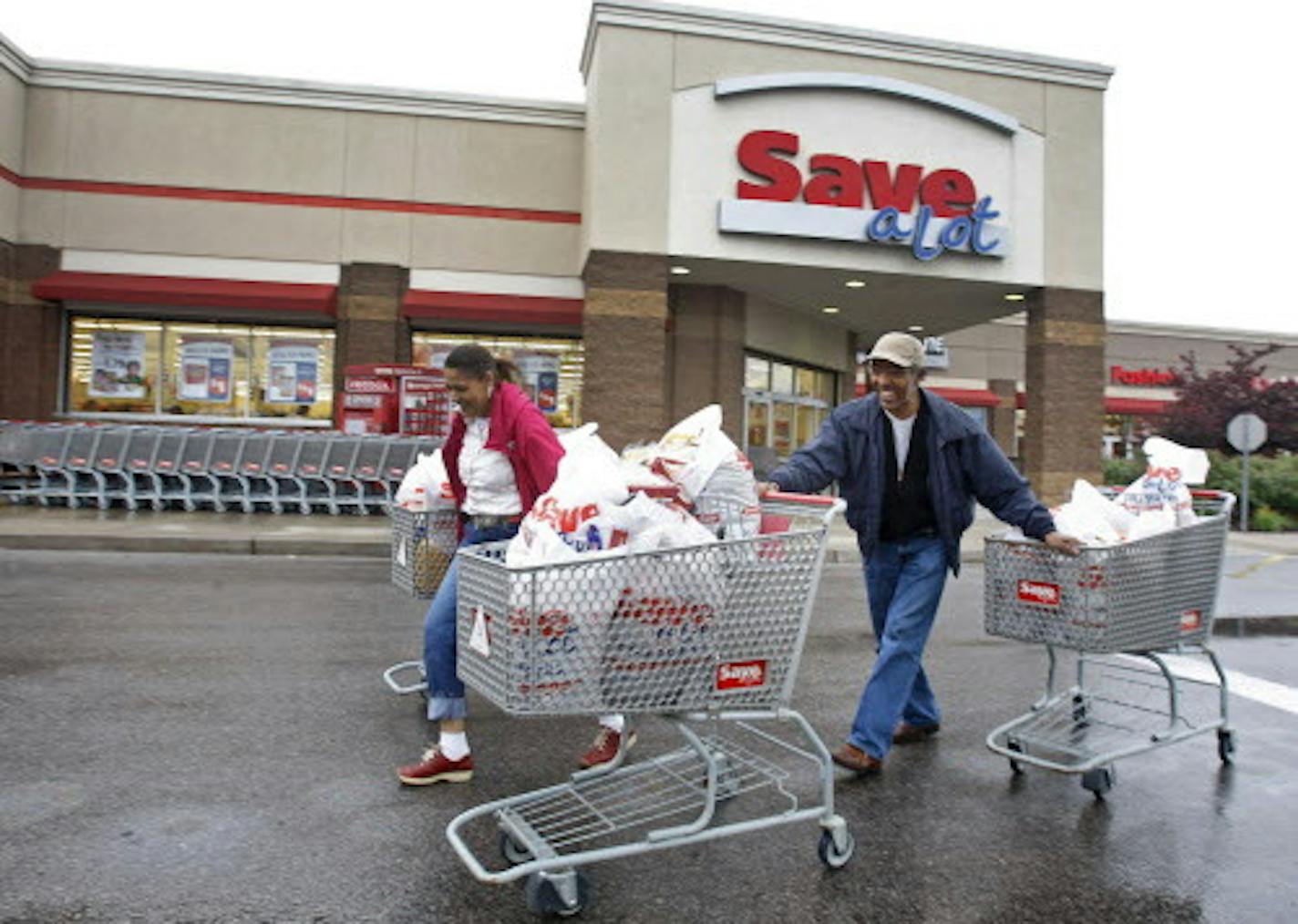 Shoppers Camelious Thompson and her brother Mark Eaton leave a Save-A-Lot store in St. Louis, Missouri, U.S., on Thursday, May 20, 2010. Supervalu Inc.'s Save-A-Lot unit, a discount grocer specializing in store-brand products, plans to expand in urban areas to fill in gaps left after larger chains moved to the suburbs. Photographer: Peter Newcomb/Bloomberg *** Local Caption *** Camelious Thompson; Mark Eaton ORG XMIT: MIN2012120516120005