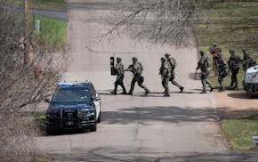 Heavily armed law enforcement personnel search the area near East Crestwood Drive where a suspect fired at and hit two Hennepin County sheriff’s dep