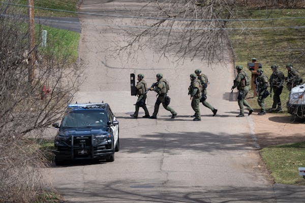 Heavily armed law enforcement personnel search the area near E. Crestwood Drive where a suspect fired at and hit two Hennepin County sheriff’s deput