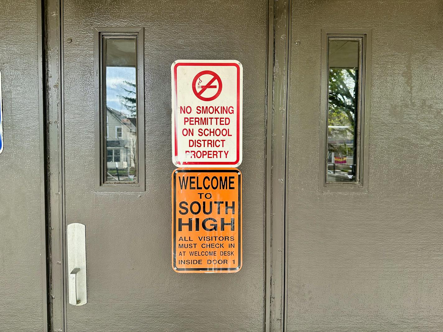 A sign on a door says "Welcome to South High." Above it is a no smoking sign.