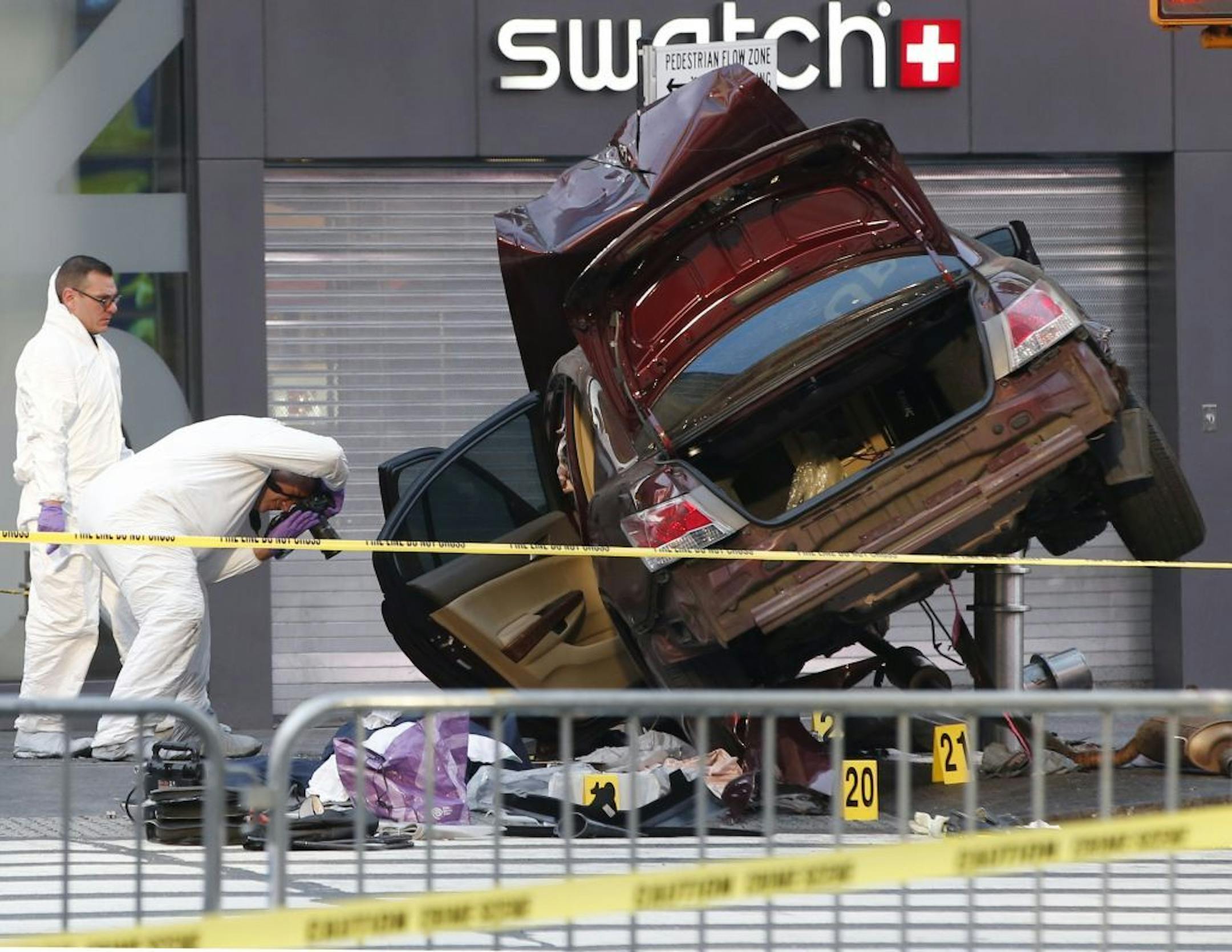 Investigators photograph evidence at the scene of a crash that killed one person and injured almost two dozen others in Times Square, Thursday, May 18, 2017, in New York. Police say a man steered his car onto a sidewalk running through the heart of Times Square mowing down pedestrians for three blocks. He then emerged from his wrecked vehicle wild-eyed and waving his arms before he was subdued by police and bystanders.