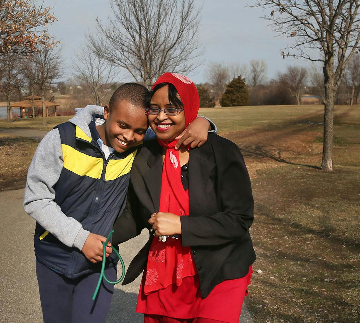 Fierce advocate Idil Abdull walks with her son Abdullahi, 12, at a Burnsville Park near their Savage home Wednesday, April 1, 2015, in Burnsville, MN. Routine, Abdul says, is important in the life of her autistic son, requiring trips to Wendy's for french fries over spring break and walks that go to familiar places and and in familiar directions.](DAVID JOLES/STARTRIBINE)djoles@startribune.com Idil Abdull, a relentless advocate for expanded autism benefits for poor families, will be walking with