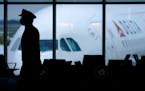 FILE - A Delta Airlines pilot wears a face mask as he walks through a terminal at Hartsfield-Jackson International Airport in Atlanta, on Thursday, Fe