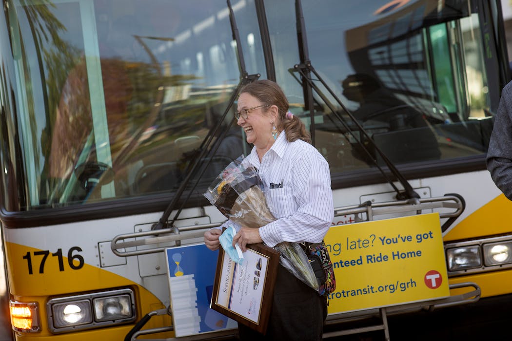 On her 45th anniversary as a bus driver, in 2021, Melanie Benson receives flowers and a plaque at one of her stops. 