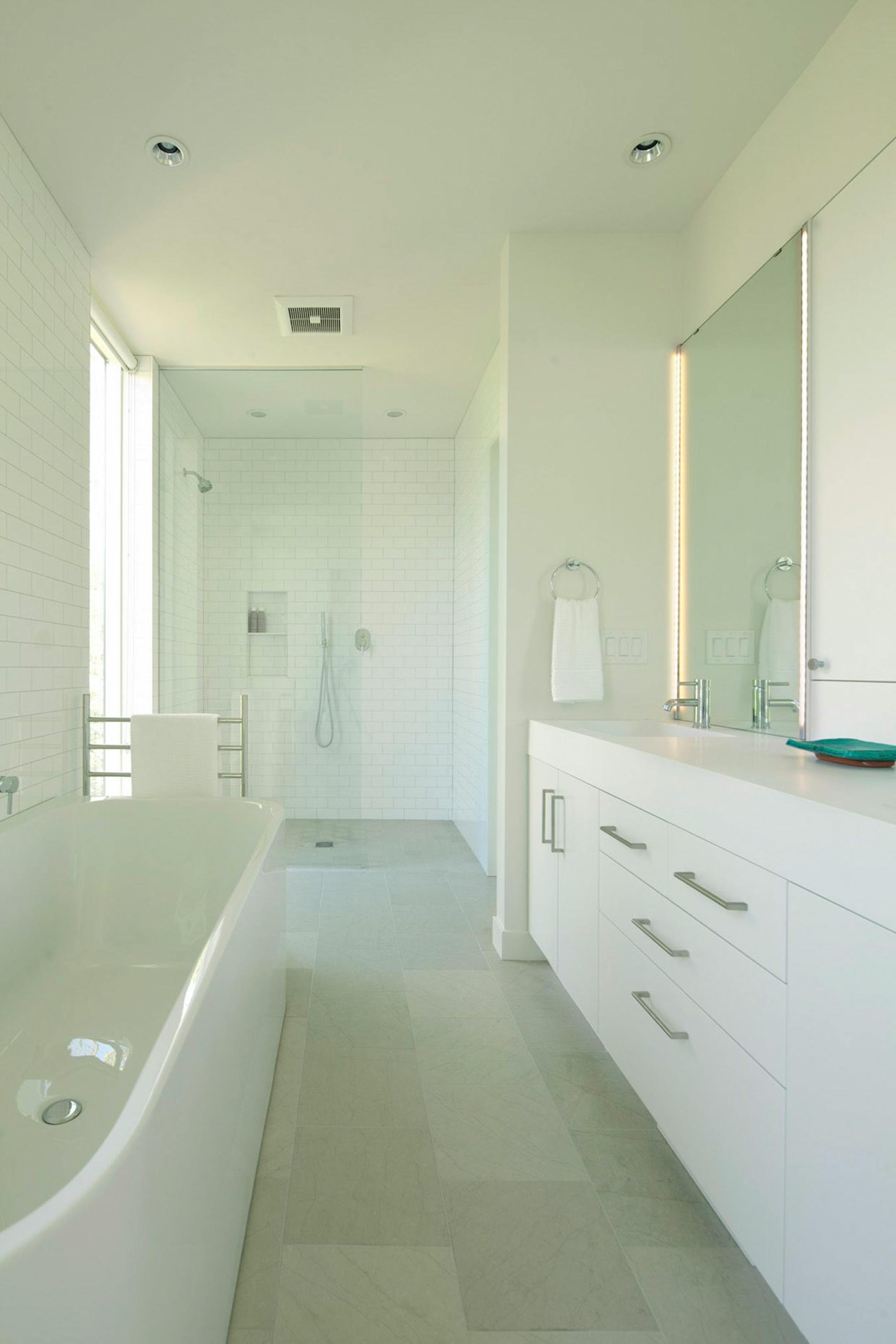 The owners' subway-tlled white bathroom has spa features such as a heated floor and towel warmer.