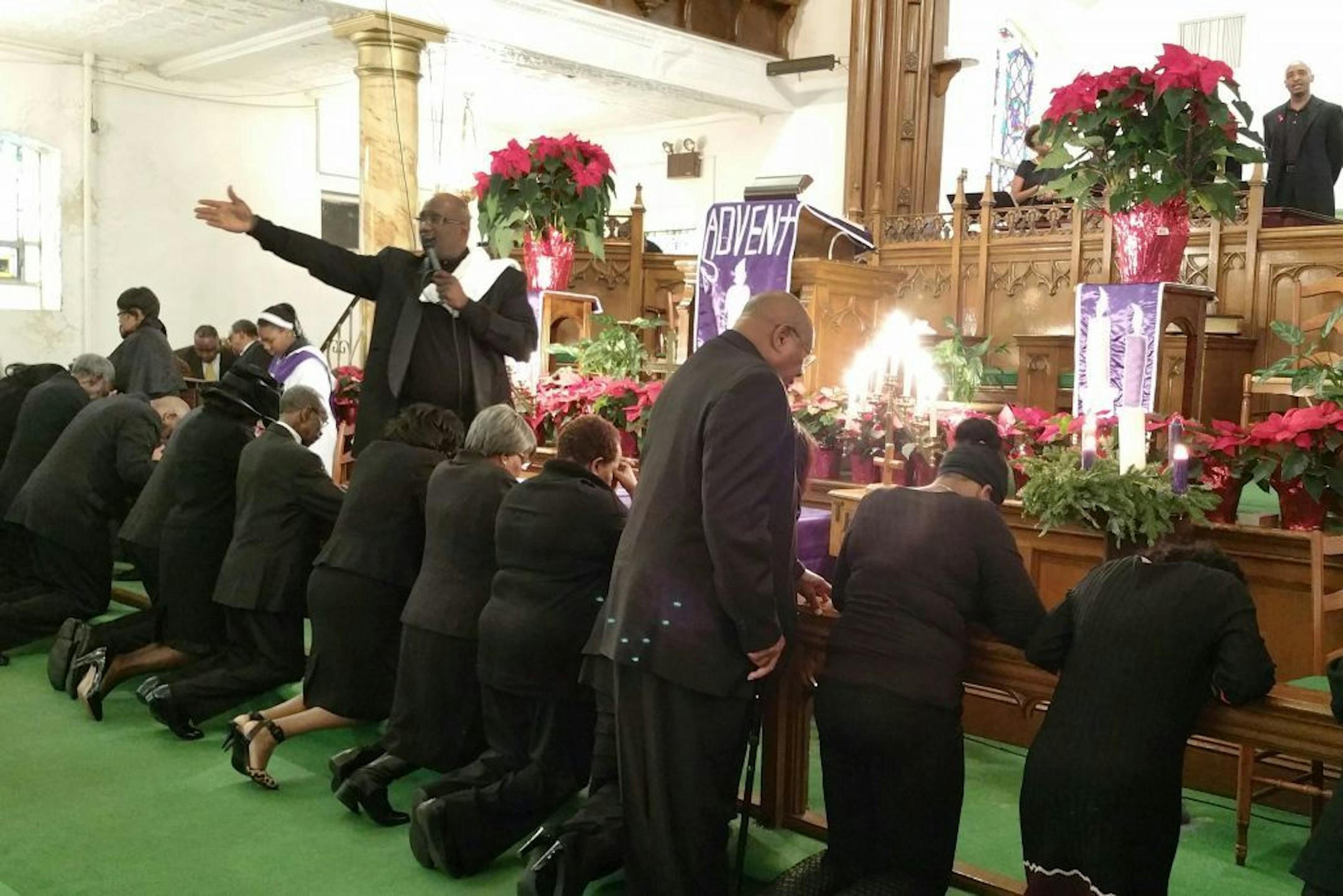 Pastor Henry A. Belin III, standing left, pastor at First AME Church: Bethel, prays over members of his congregation, Sunday, Dec. 14, 2014 in New York. Congregants in African-American churches across the country wore black to Sunday services and prayed over the men in attendance in a symbolic stand against fatal police shootings of unarmed black men.