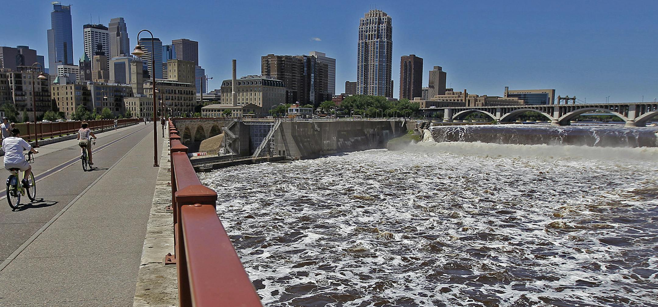 Pedestrians and bikers made their way across the Stone Arch Bridge as the water raged beneath them, Thursday, June 27, 2013. Three locks on the Mississippi River in the Twin Cities closed to all boat traffic due to high water. (ELIZABETH FLORES/STAR TRIBUNE) ELIZABETH FLORES • eflores@startribune.com