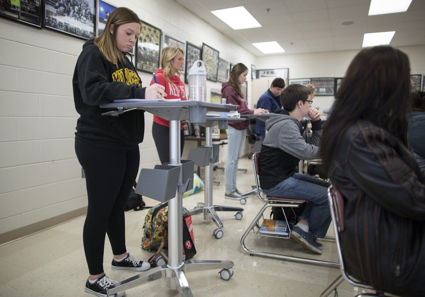 Students across the state are ditching seats for taller standing desks, which advocates are saying will boost test scores and burn calories. Here, senior Alyssa Reinke (left) and Madison Staggert (in Red) and a few other students at Andover High School are using stand up desks in U.S. Government and Politics class. ] Brian.Peterson@startribune.com Andover, MN - 11/24/2015