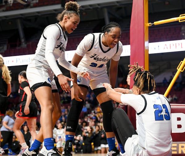 Hopkins guard/forward Taylor Woodson (20) and guard NuNu Agara (24) celebrate with guard Liv McGill (23) after McGill scored with an and-one opportuni