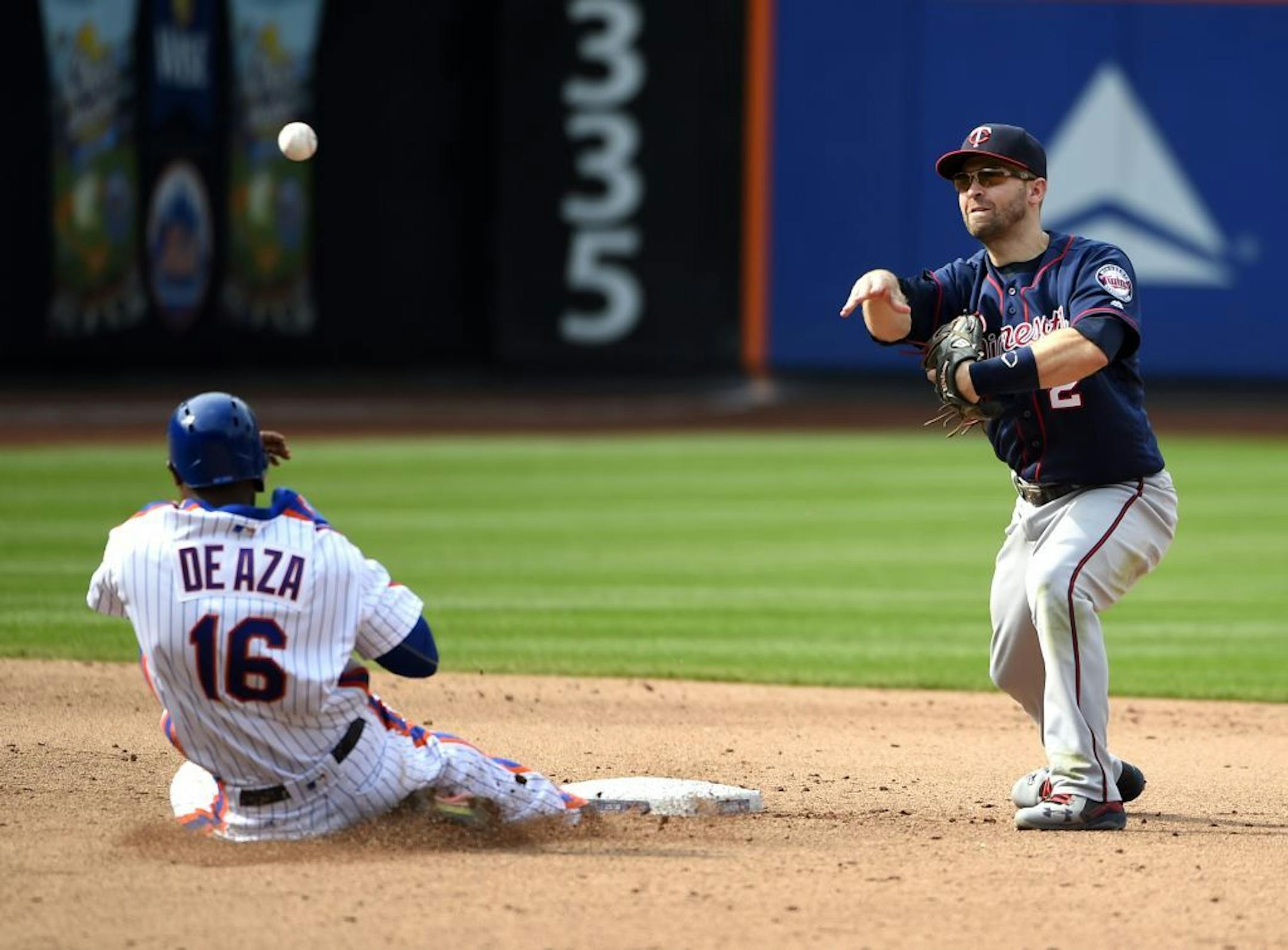 Minnesota Twins second baseman Brian Dozier forces out New York Mets Alejandro De Aza and throws to first base to complete the double play in the fifth inning of a baseball game, Sunday, Sept. 18, 2016, in New York.