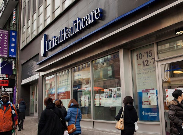 Pedestrians pass in front of a UnitedHealthcare store in the Queens borough of New York, U.S., on Monday, Jan. 14, 2013. The experiment to sell health