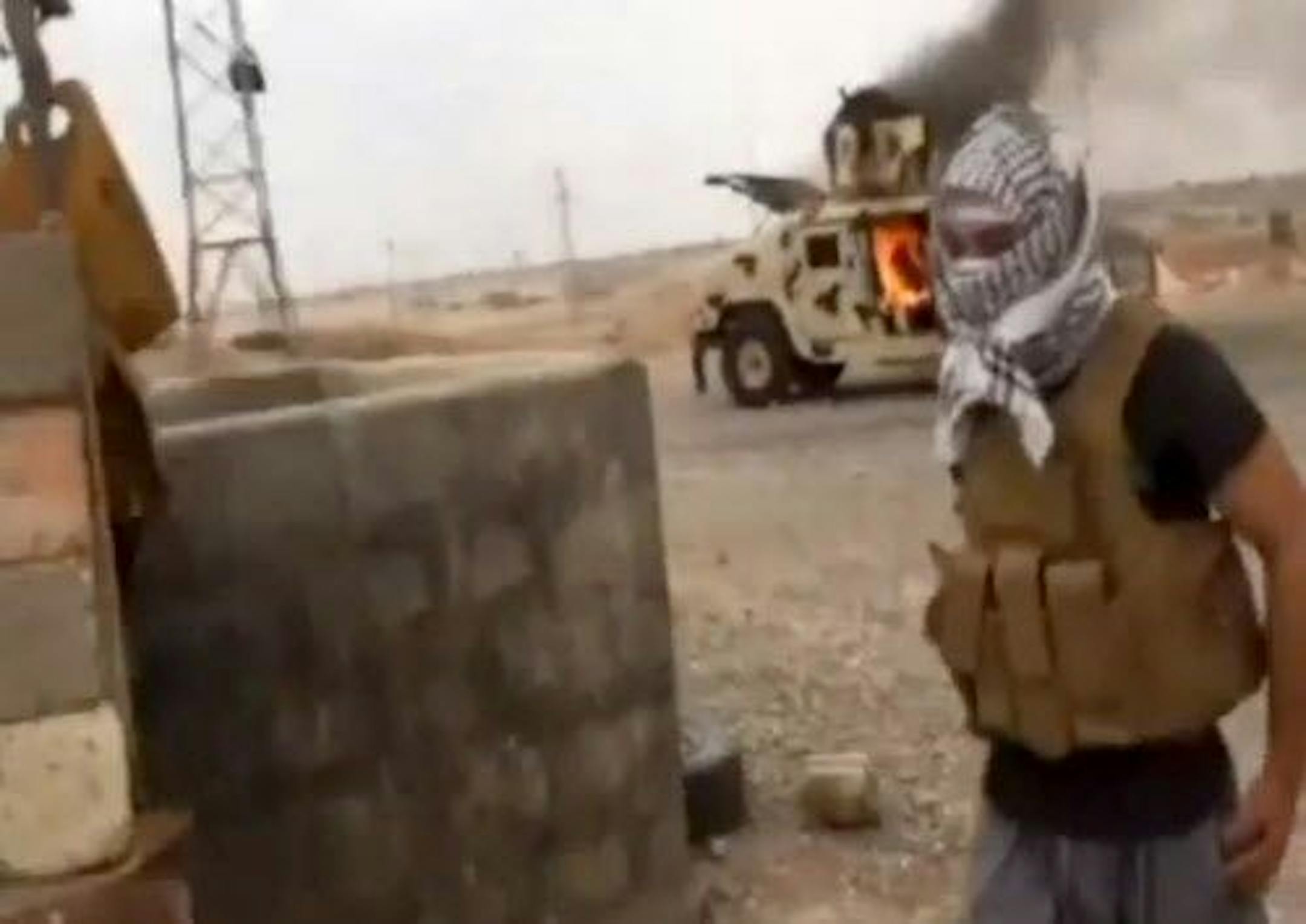 This image made from video posted by a pro-insurgency group shows a militant standing in front of a burning Iraqi Army Humvee in Tikrit, Iraq.
