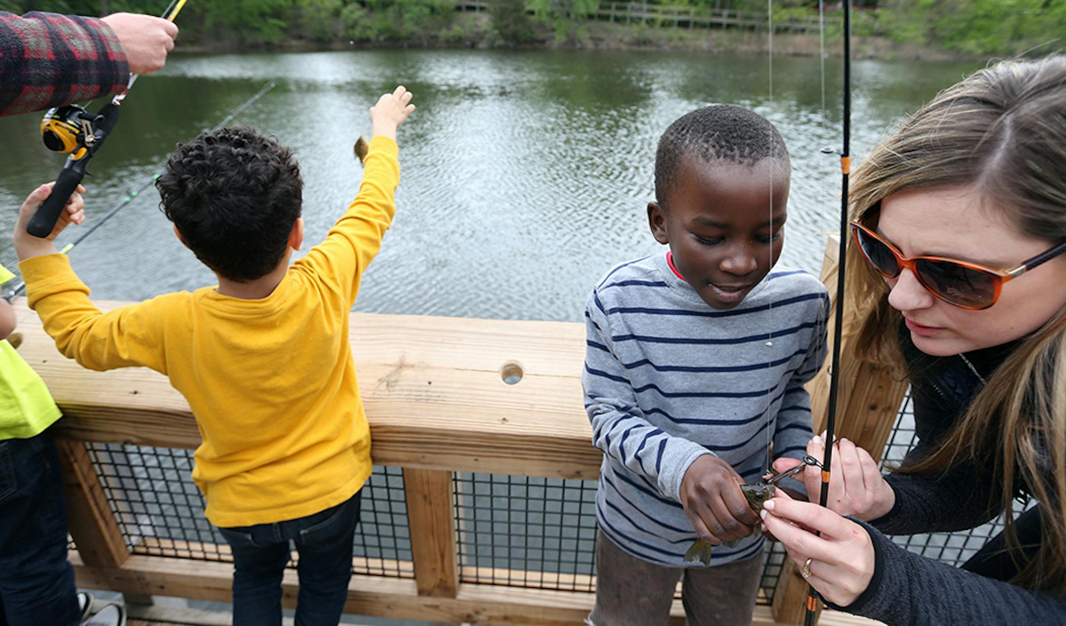 Dean Ototo a third grader at School of Engineering Arts got help from Suzanne Thomson removing a sunfish from a hook at Wolfe Lake.