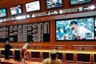 FILE - In this Monday, May 14, 2018 file photo, people make bets in the sports book area of the South Point Hotel and Casino in Las Vegas. Those who d