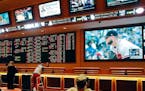 FILE - In this Monday, May 14, 2018 file photo, people make bets in the sports book area of the South Point Hotel and Casino in Las Vegas. Those who d