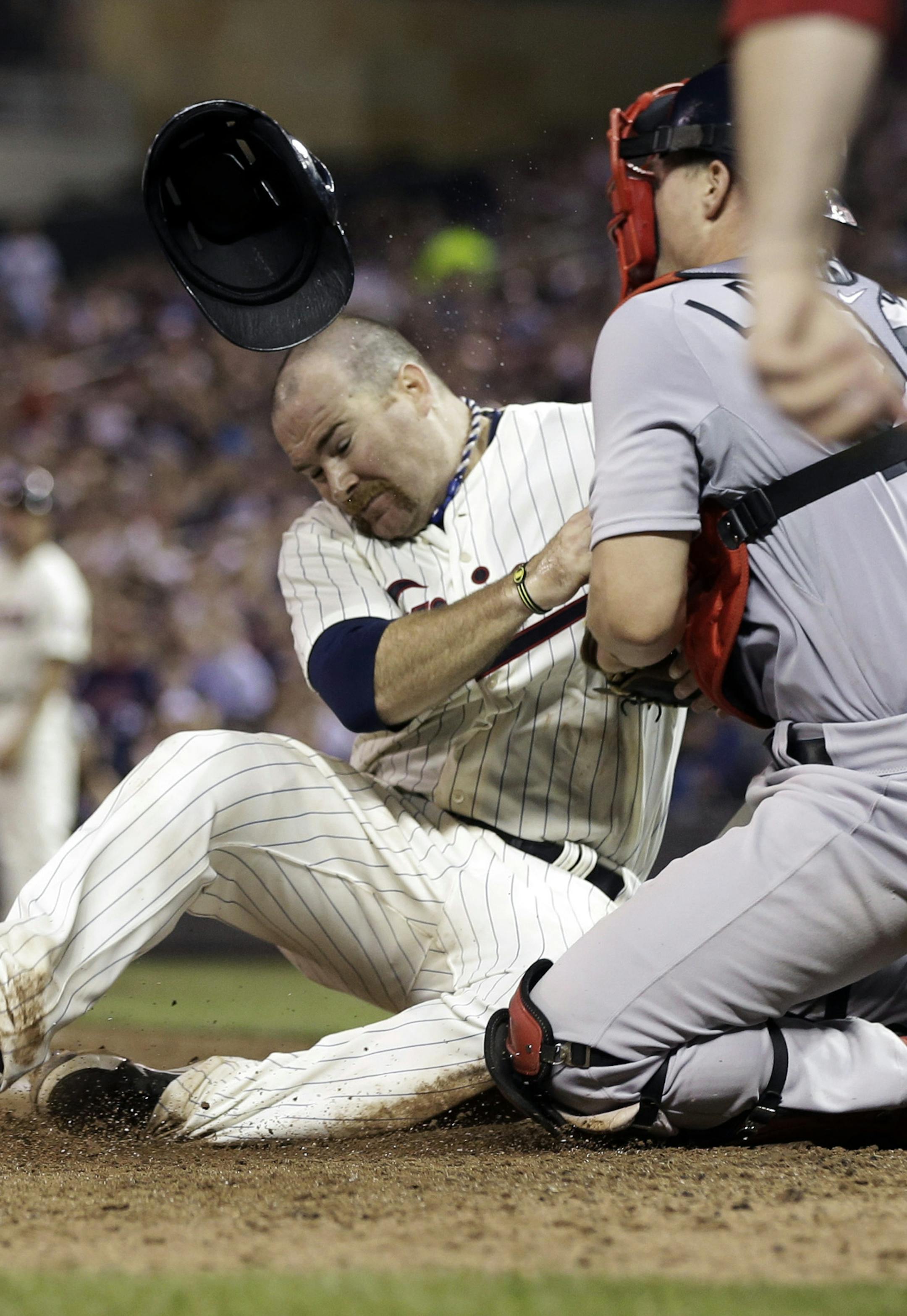 Minnesota Twins' Ryan Doumit, left, loses his helmet as he collides with Boston Red Sox catcher Ryan Lavarnway, who tagged Doumit out as he tried to score from third on a fly out by Aaron Hicks in the sixth inning of a baseball game, Saturday, May 18, 2013, in Minneapolis. (AP Photo/Jim Mone)