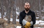 Jonathan C. Slaght and one of the female fish owls he caught and tracked in Russia. (The owl holds a fish in its beak.)