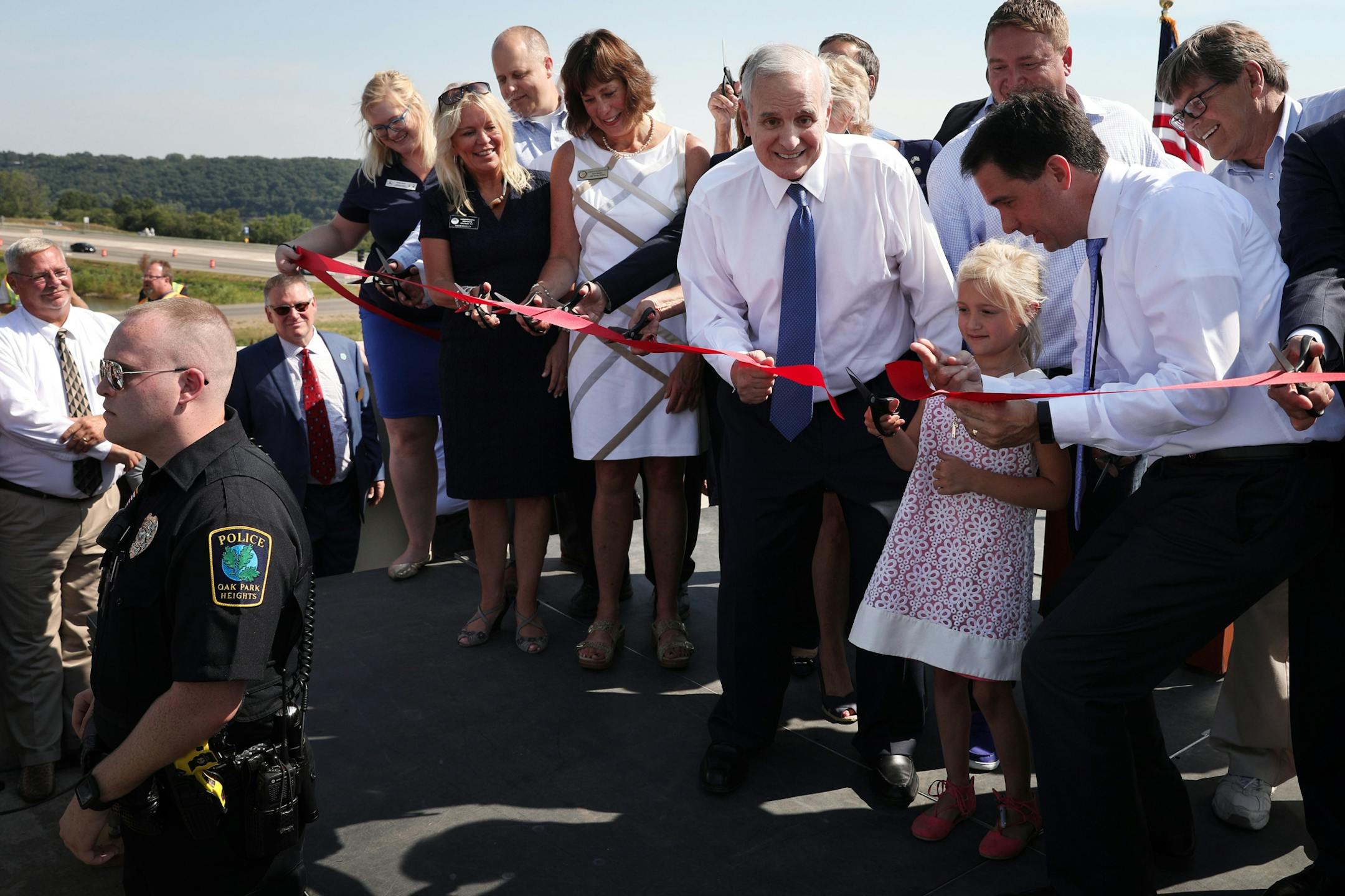 Minnesota Gov. Mark Mark Dayton and Wisconsin Gov. Scott Walker stood with Evie Kozlowski, 7, as she cut the second ribbon.