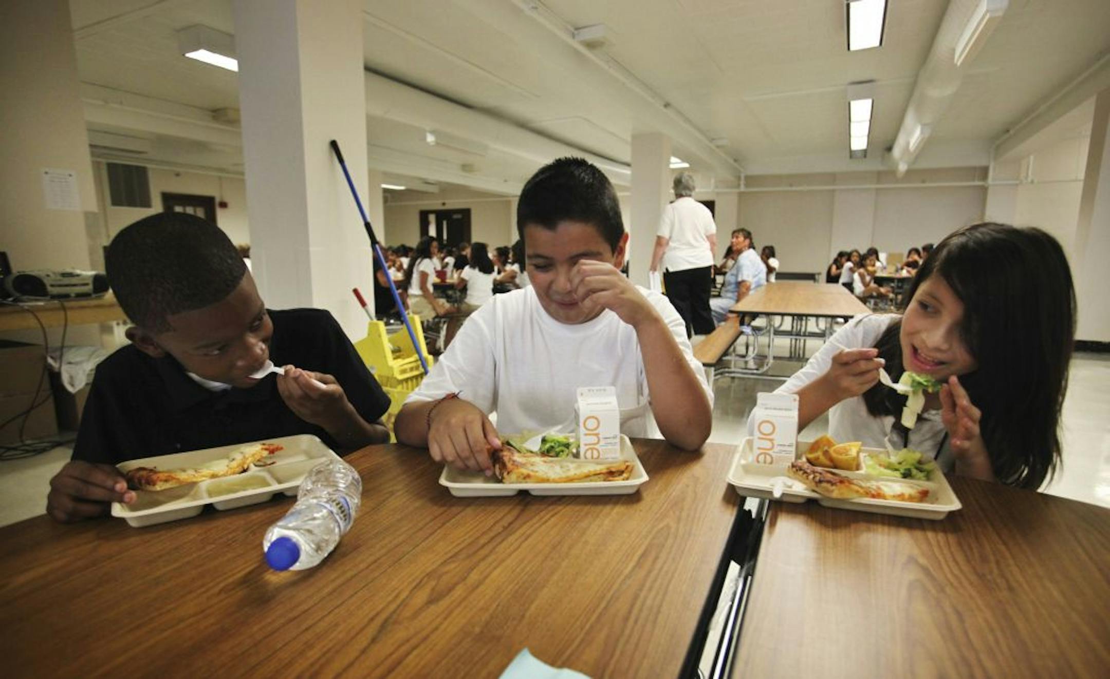 Fifth-graders Rajaun Lambert, left, Felipe Santana and Carla Aranda Quiroz ate a lunch of pizza, salad and fruit at Folwell School.