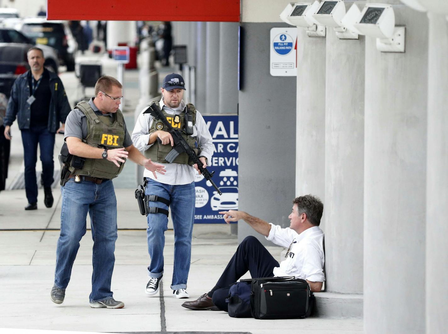 A law enforcement officers talk to a man at Fort Lauderdale�Hollywood International Airport, Friday, Jan. 6, 2017, in Fort Lauderdale, Fla. A gunman opened fire in the baggage claim area at the airport Friday, killing several people and wounding others before being taken into custody in an attack that sent panicked passengers running out of the terminal and onto the tarmac, authorities said.