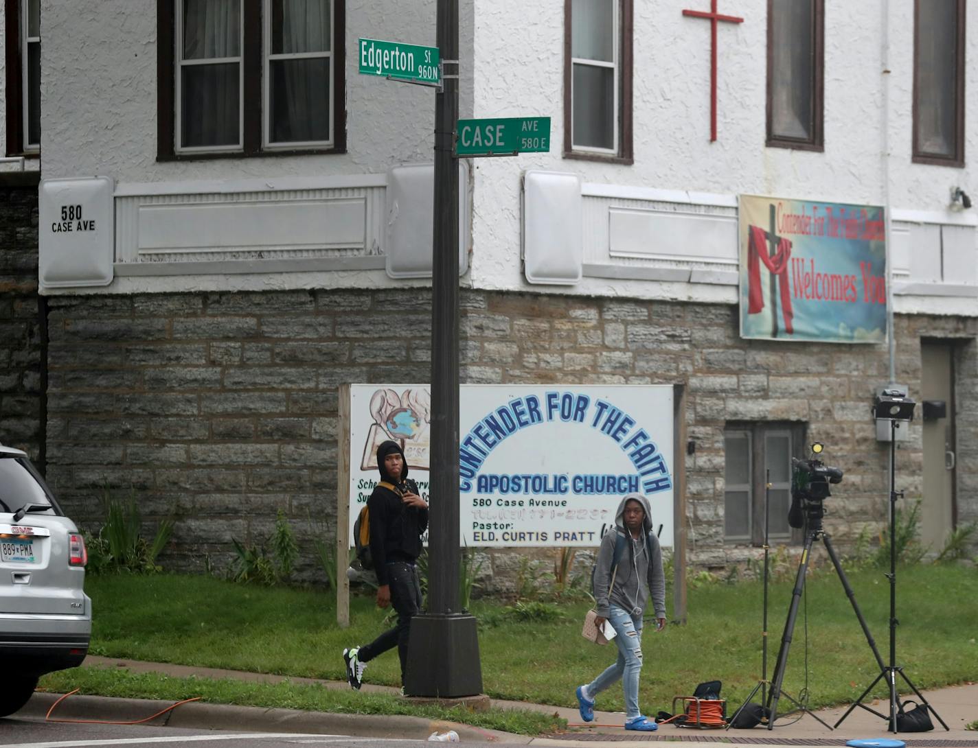 Pedestrians walk by the scene of a car accident and shooting at Edgerton St. and Case Ave on Tuesday in St. Paul. The shooting occurred overnight.