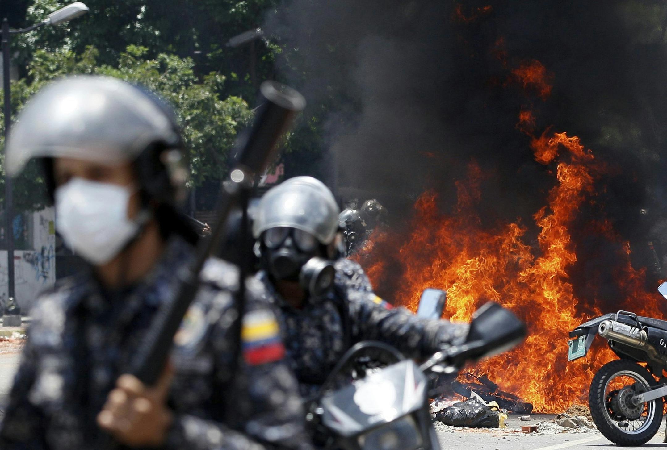 Venezuelan Bolivarian National police move away from the flames after an explosion at Altamira square during clashes against anti-government demonstrators in Caracas, Venezuela, Sunday, July 30, 2017. The explosion injured several officers and damaged several of their motorcycles. The officers were then seen throwing several privately owned motorcycles into the remaining fire in reprisal. (AP Photo/Ariana Cubillos)