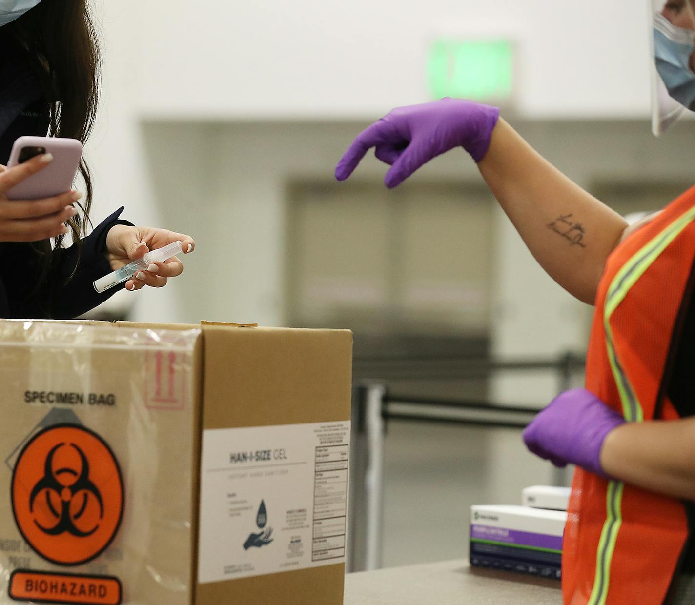 People at a new saliva testing center for COVID in the Minneapolis Convention Center drop saliva samples into a collection box Monday in Minneapolis. Yesterday Minnesota reached an all-time high daily COVID count at nearly 6,000 as the U.S. today surpassed 10 million total cases. ] DAVID JOLES • david.joles@startribune.com Monday, Nov. 9, 2020 in Minneapolis, MN new saliva testing center for COVID