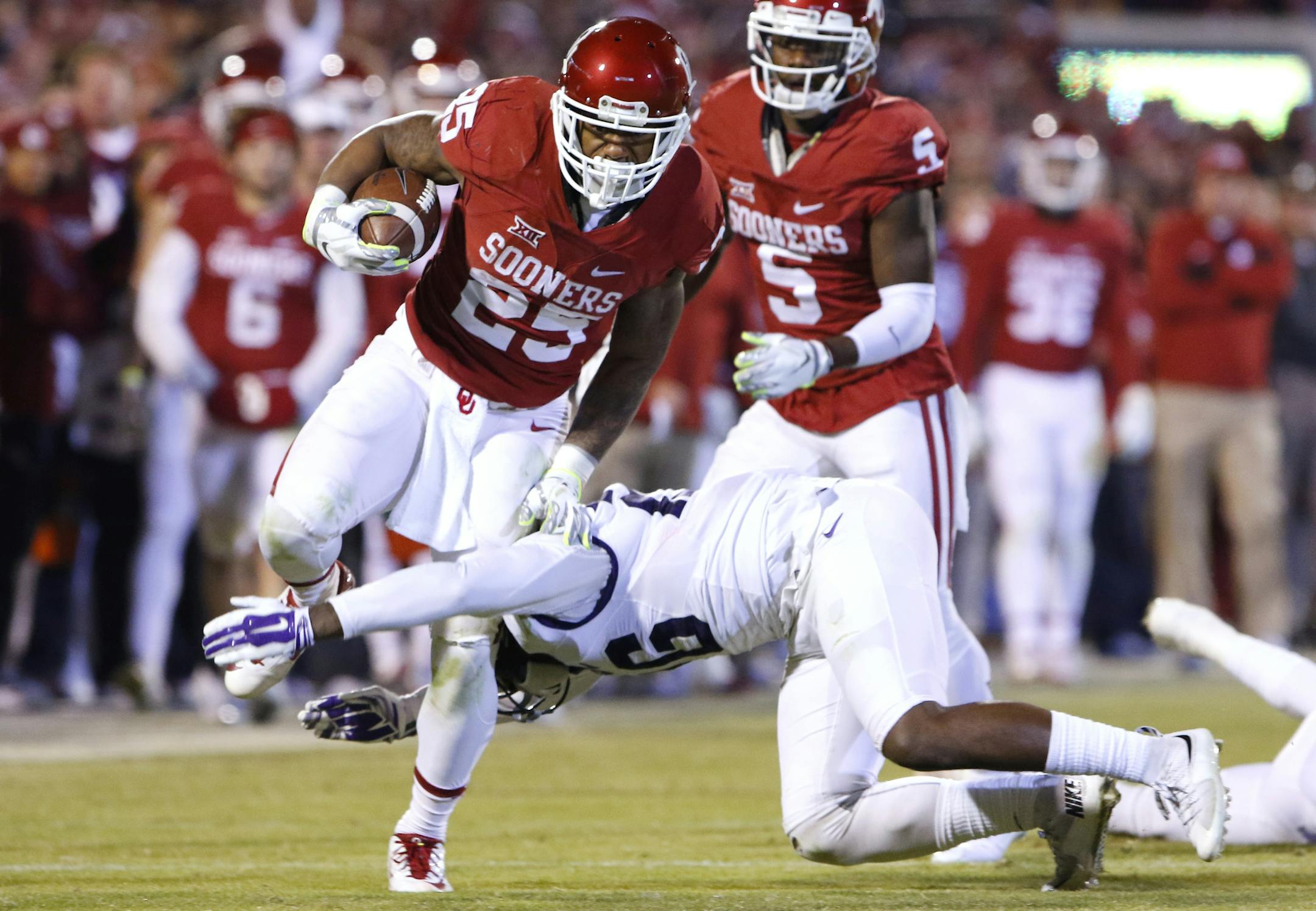 Oklahoma running back Joe Mixon (25) is tackled by TCU safety Derrick Kindred (26) during the fourth quarter of an NCAA college football game in Norman, Okla., Saturday, Nov. 21, 2015. Oklahoma won 30-29. (AP Photo/Alonzo Adams)