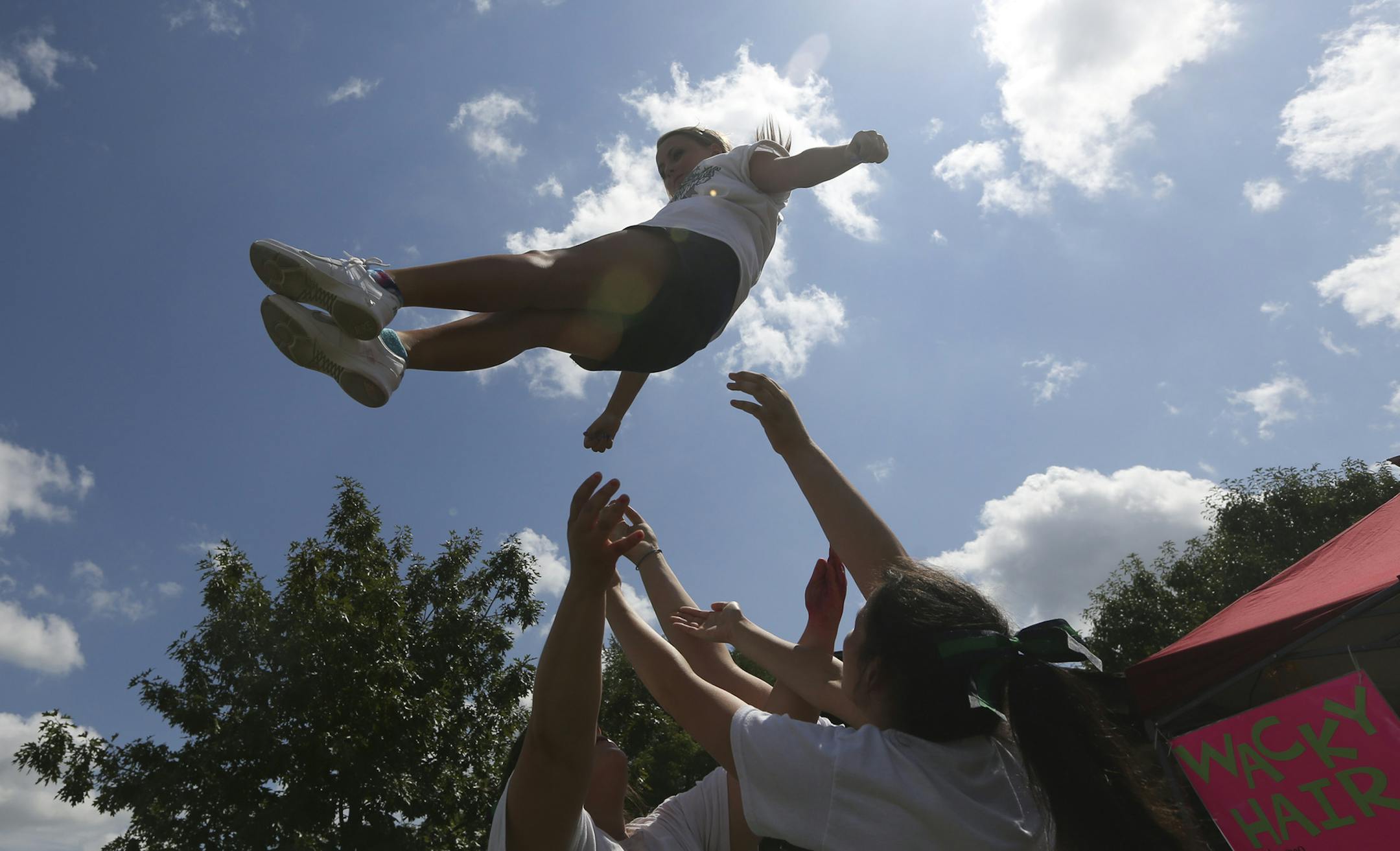 Morgan Reibly a sophomore at Rosemount High School, prepared to be caught by her cheerleading teammates as they try to drum up customers for the their wacky hair booth at the Leprechaun Days in Rosemount, Min., Saturday, July 28, 2012. ] (KYNDELL HARKNESS/STAR TRIBUNE) kyndell.harkness@startribune.com