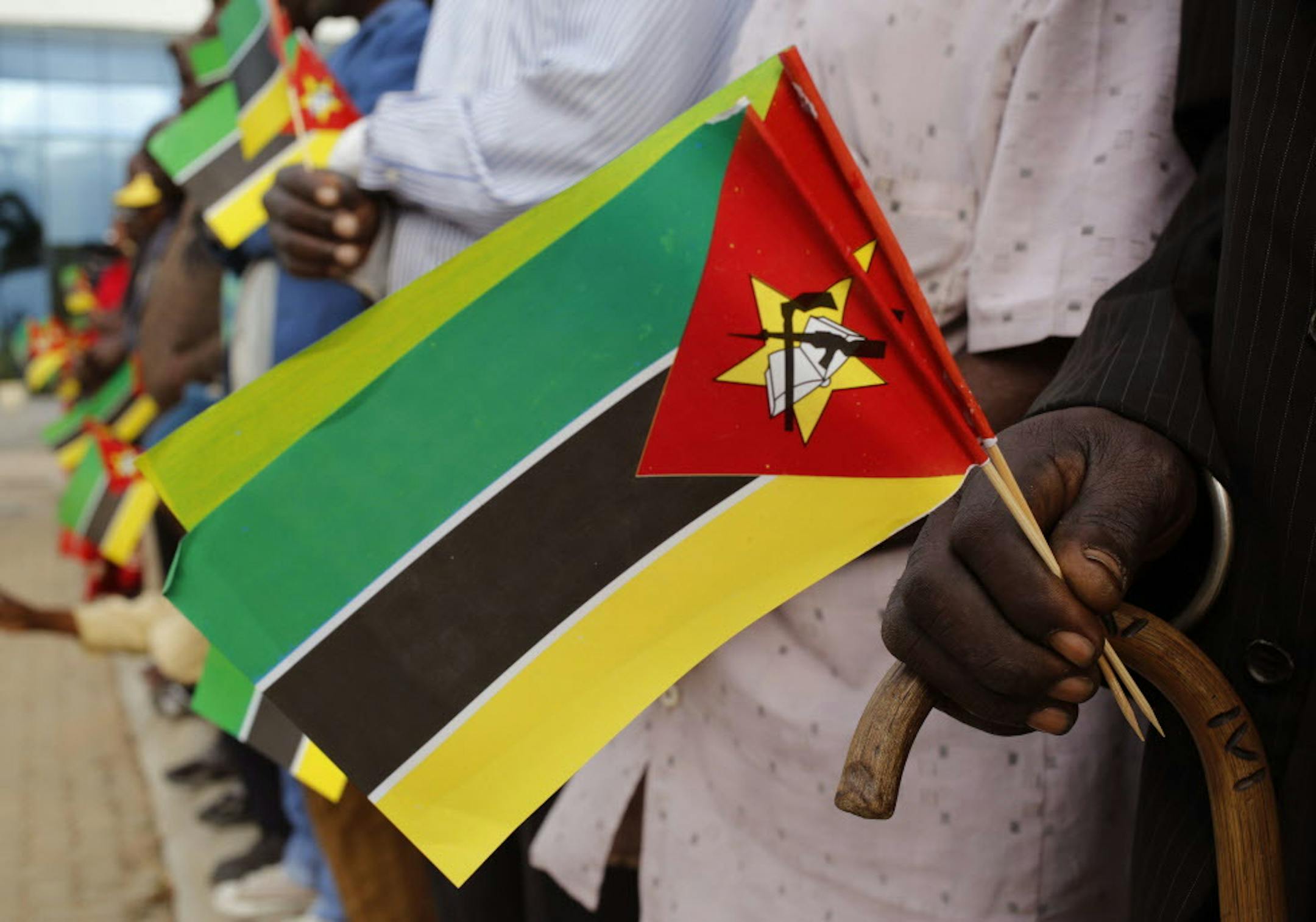 An old man holds Mozambican flag as people wait for the arrival of India's Prime Minister Narendra Modi at a technical school in Maluana, Mozambique, Thursday, July 7, 2016. Modi on Thursday kicked off a four-nation African tour on a continent where China's presence has been strong, including countries that haven't been visited by an Indian leader in more than three decades. (AP Photo/Schalk van Zuydam)